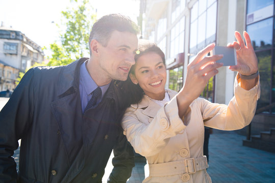 Cheerful couple making selfie photo in the city