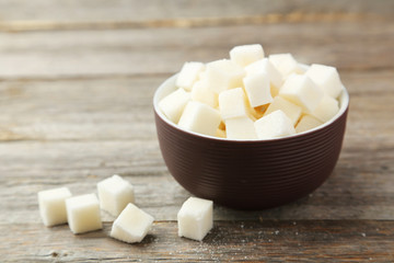 Sugar cubes in bowl on grey wooden background