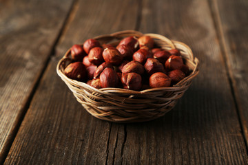 Hazelnuts in basket on brown wooden background