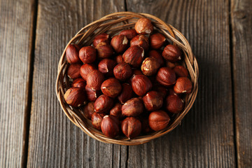 Hazelnuts in basket on brown wooden background