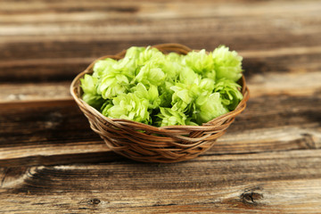 Hops in basket on brown wooden background