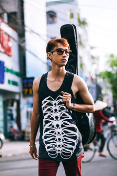 asian guitarist artist man walk on vietnamese street