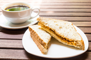 Sandwich bread servedwith black coffee at background