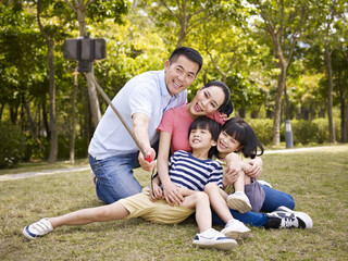 happy asian family taking a selfie with selfie stick