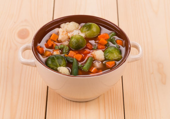 Fresh vegetable soup with sausage on wood.
