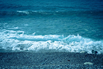 Sea wave foam on the pebble beach. Toned