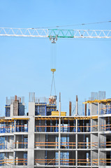 Crane lifting concrete mixer container against blue sky