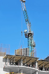 Crane hoisting formwork over construction site work