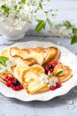 Heart shaped pancakes with berries of currant and honey