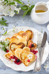 Heart shaped pancakes with berries of currant and honey