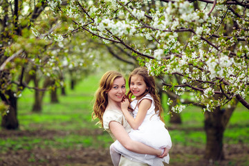 Fototapeta premium Happy mother and daughter in the flowered garden