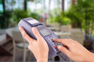 Woman hand with credit card swipe through terminal for sale in restaurant