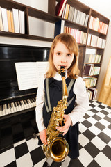 Cute girl in dress plays on the alto saxophone