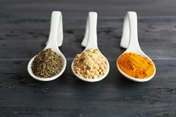 Different kinds of spices in spoons on wooden background
