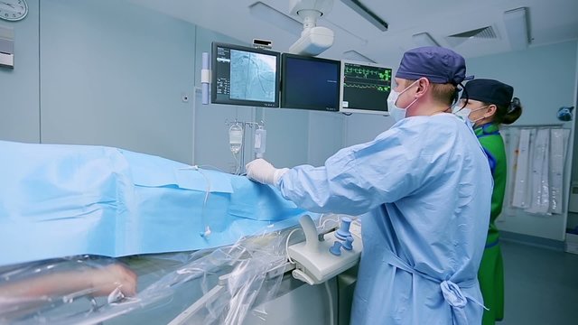 A surgeon manipulates medical equipment
