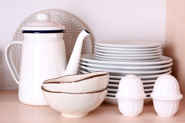 Kitchen utensils and tableware on wooden shelf