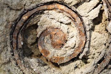 Rusty metal spiral with cement, closeup