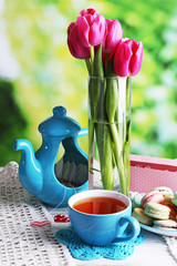 Composition of spring flowers, tea and cookies on table on natural background