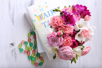 Beautiful fresh spring flowers with stack of books, top view