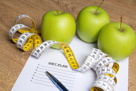 diet concept - close up of paper with diet plan, apples and meas