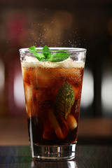 Glass of cocktail in bar on bright blurred background