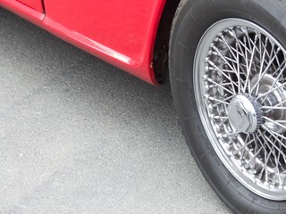 Chromspeichenrad mit Zentralverschluss eines roten englischen Roadster der Sechziger Jahre am...