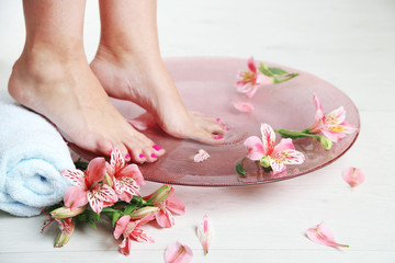 Fototapeta na wymiar Woman washing beautiful legs in bowl, on light background. Spa procedure concept