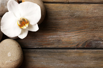 Obraz na płótnie Canvas Spa stones and orchid flower on wooden background