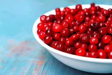 Cranberries in bowl on wooden background