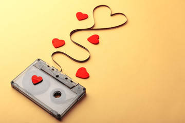 Audio cassette with magnetic tape in shape of heart on yellow background