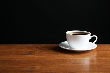 Cup of coffee on table on dark background