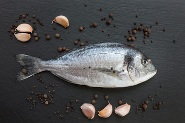Fresh dorado fish on slate cutting board with garlic