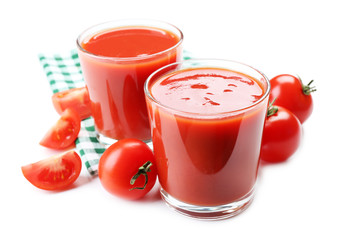 Glasses of fresh tomato juice on checkered napkin, isolated on white