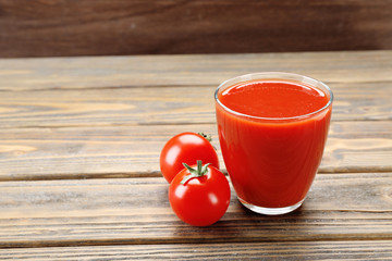 Glass of fresh tomato juice on wooden background