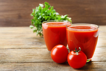 Glasses of fresh tomato juice on wooden background