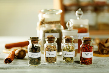Assortment of spices in glass bottles on wooden background
