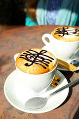 Cups of cappuccino with treble clef on foam on table in cafe