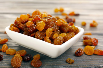 Raisins in saucer on wooden table, closeup
