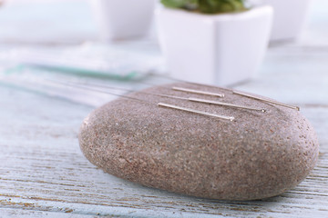 Acupuncture needles with spa stone on wooden table, closeup
