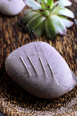 Acupuncture needles with spa stone on tray, closeup