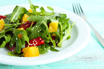 Tasty salad with arugula leaves in plate on wooden table, closeup