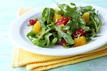 Tasty salad with arugula leaves in plate on wooden table, closeup