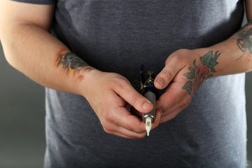 Hand of tattoo artist with tattoo machine, closeup