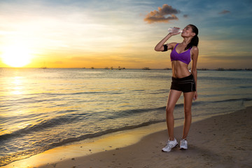Fototapeta na wymiar Sporty young woman drinking water