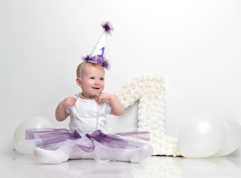 Little happy toddler baby girl celebrating first birthday sittin