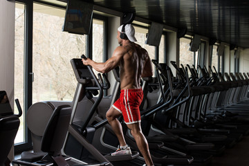 Plakat Mature Man Doing Aerobics Elliptical Walker In Gym