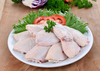 Raw chicken wings with vegetables on wooden board