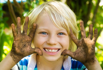 Happy boy playing outdoors with dirty hands