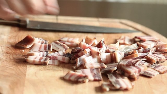 chef finely chopping smoked bacon - closeup
