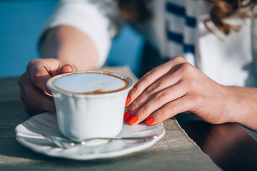 beautiful young girl in outdoor cafe reading a book and drinking